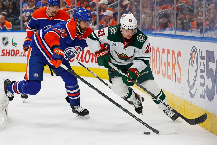 Edmonton Oilers defensemen Darnell Nurse (25) and Minnesota Wild forward Brandon Duhaime (21) battle along the boards for a loose puck
