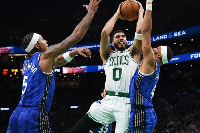 Boston Celtics forward Jayson Tatum (0) drives to the basket between Orlando Magic forward Paolo Banchero (5) and guard Jalen Suggs (4) during the second half at TD Garden