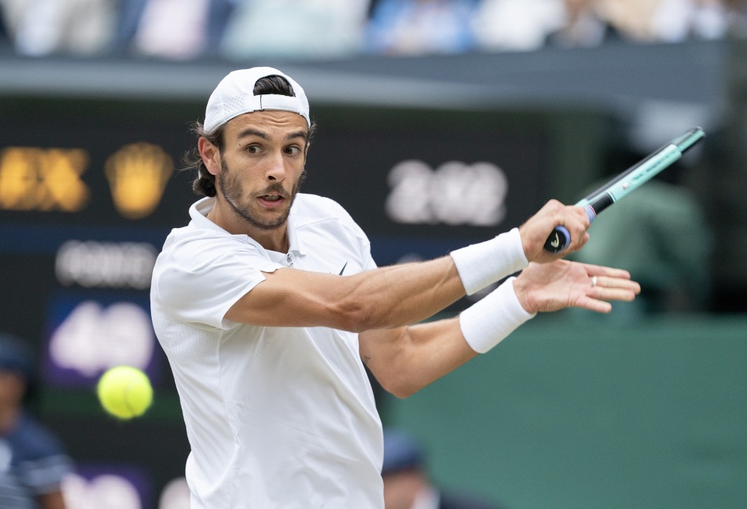 Lorenzo Musetti hits a backhand in his match against Novak Djokovic at Wimbledon.