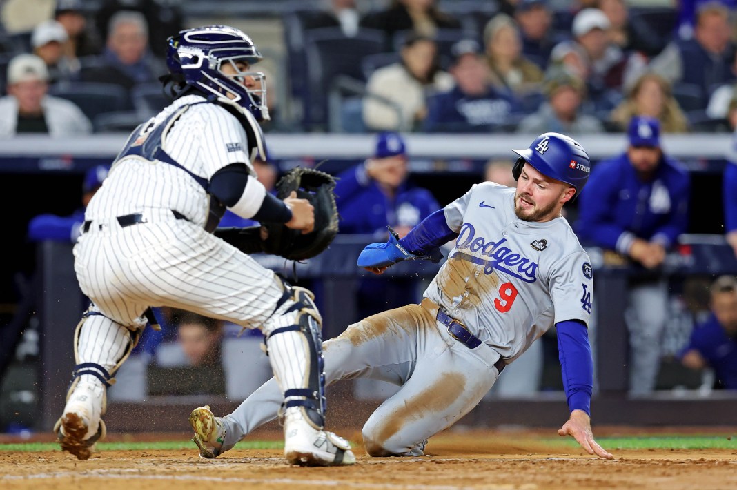 Los Angeles Dodgers second baseman Gavin Lux slides into home plate to score a run ahead of the tag of New York Yankees catcher Jose Trevino.