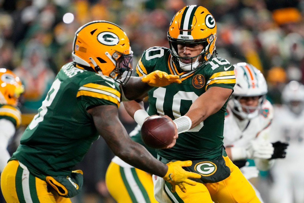 reen Bay Packers quarterback Jordan Love hands the football off to running back Josh Jacobs