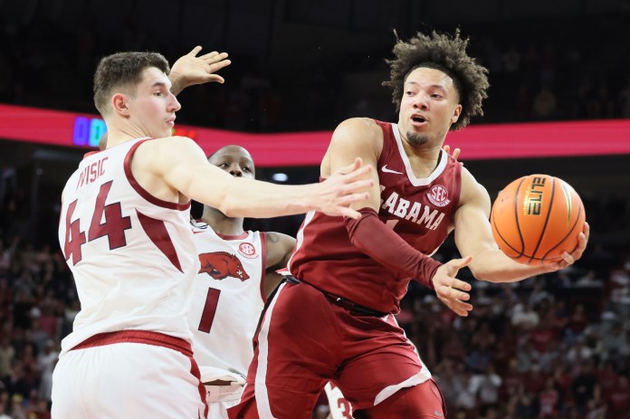 Alabama Crimson Tide guard Mark Sears (1) passes the ball in the second half as Arkansas Razorbacks forward Zvonimir Ivisic (44) defends at Bud Walton Arena on February 8, 2025. Alabama won 85-81.