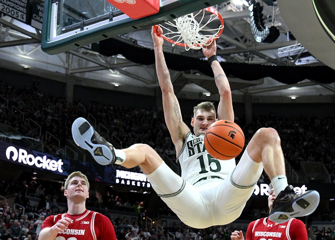 Michigan State Spartans center Carson Cooper (15) makes a big dunk on a lob pass in front of Wisconsin Badgers forward Steven Crowl (22) during the second half at Jack Breslin Student Events Center on March 2, 2025.