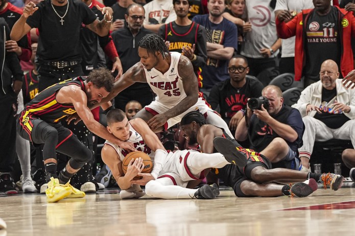 Miami Heat guard Tyler Herro (14) and guard Davion Mitchell (45) fight for the ball with Atlanta Hawks guard Trae Young (11) during overtime at State Farm Arena in Atlanta, Georgia, on April 18, 2025.