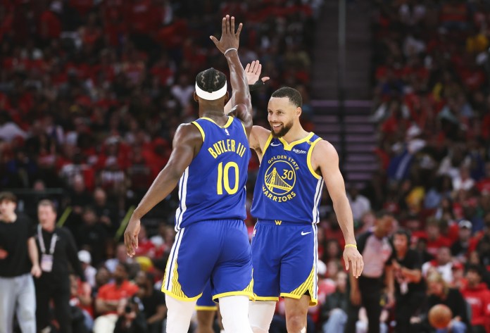 Warriors stars Stephen Curry and Jimmy Butler high five during a game against the Rockets in the 2024-25 NBA Playoffs.