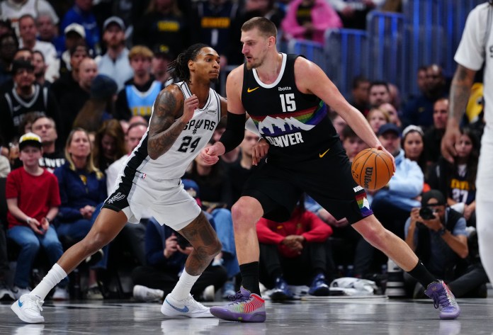 Nuggets superstar Nikola Jokic backs down Spurs guard Devin Vassell during the 2025-26 NBA season.