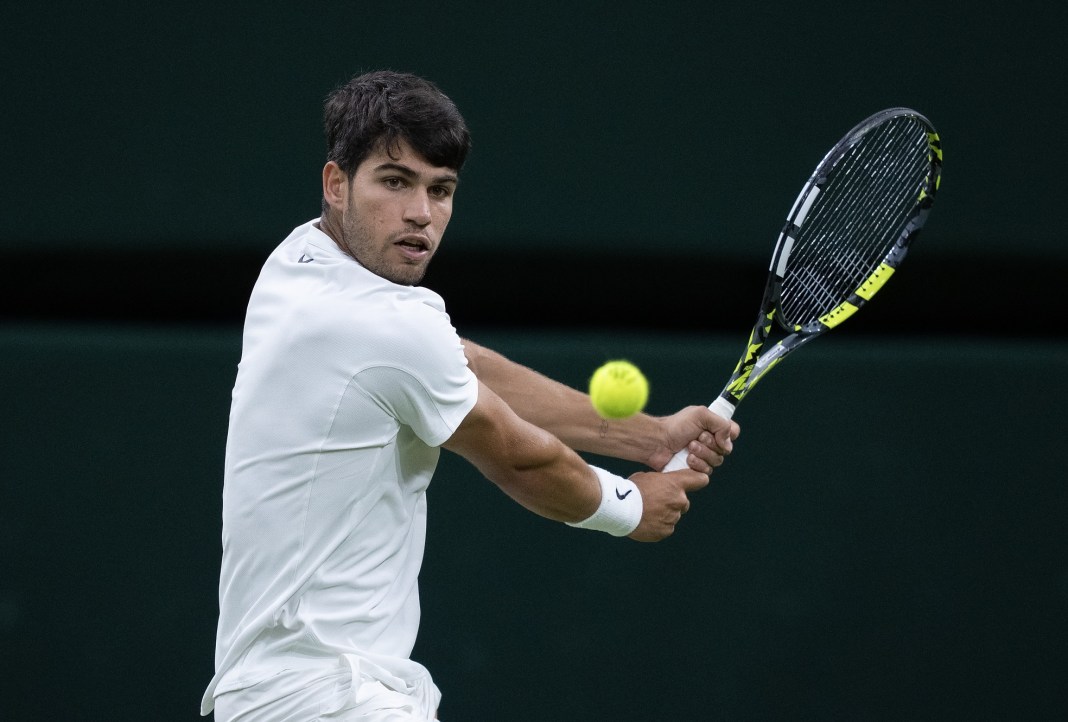 Carlos Alcaraz hits a backhand against Andrey Rublev at Wimbledon in 2025.