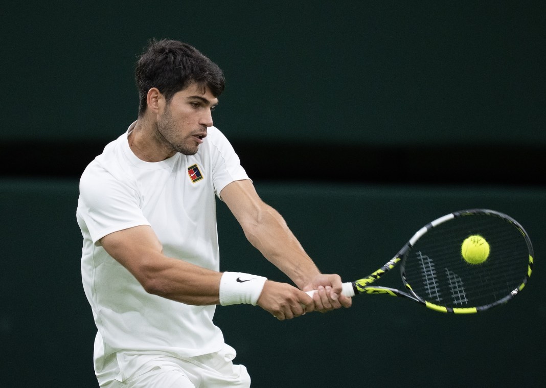 Carlos Alcaraz hits a backhand against Andrey Rublev at Wimbledon in 2025.