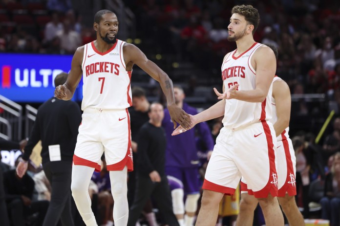 Rockets stars Kevin Durant and Alperen Sengun chat during a 2025-26 NBA preseason game against the Jazz.