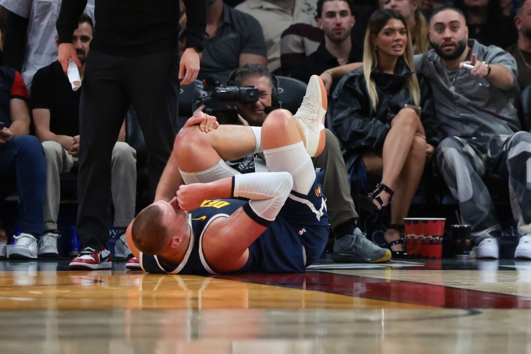 Nuggets superstar Nikola Jokic goes down with a knee injury against the Heat during the 2025-26 NBA season.