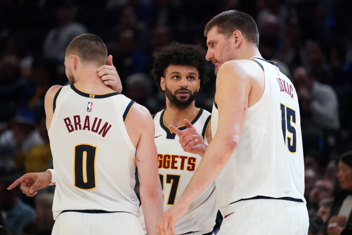 Nuggets players Nikola Jokic, Jamal Murray, and Christian Braun huddle against the Warriors during the 2025-26 NBA season.