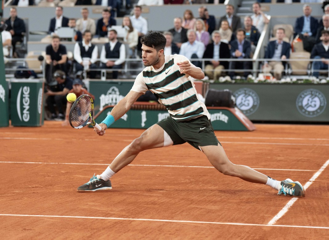 Carlos Alcaraz hits a backhand at the 2025 French Open at Roland Garros.
