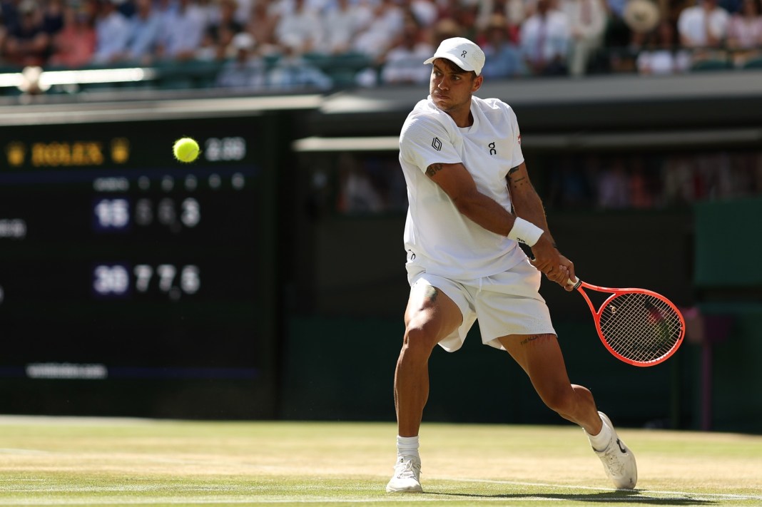 Flavio Cobolli hits a backhand against Alex de Minaur at the 2026 Wimbledon Championships.